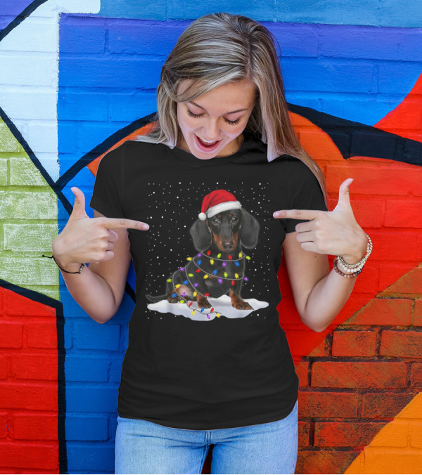 Dachshund Santa Hat Wrapped In Christmas Tree Lights In Snow With Falling Snowflakes T-Shirt