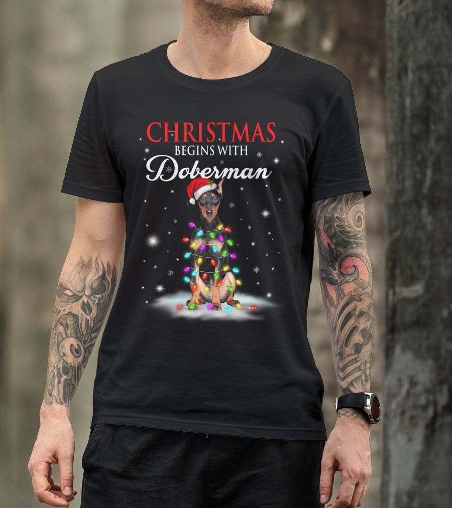 Christmas Begins With Doberman Wrapped In Holiday Lights And Santa Hat Snowflakes T-Shirt